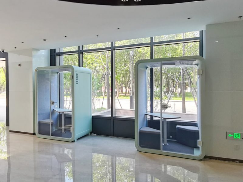 Two light green office privacy pods are placed in lobby