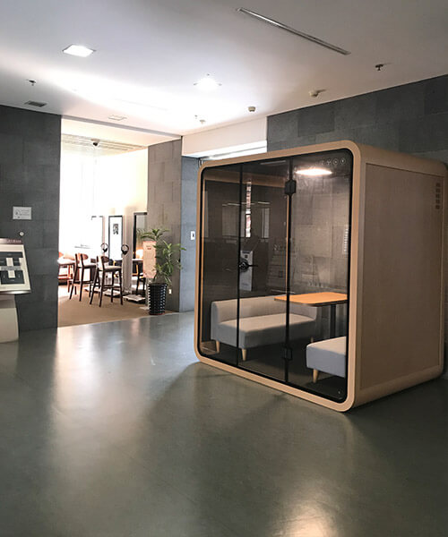 Soundbox's large khaki office privacy pod is placed in open office