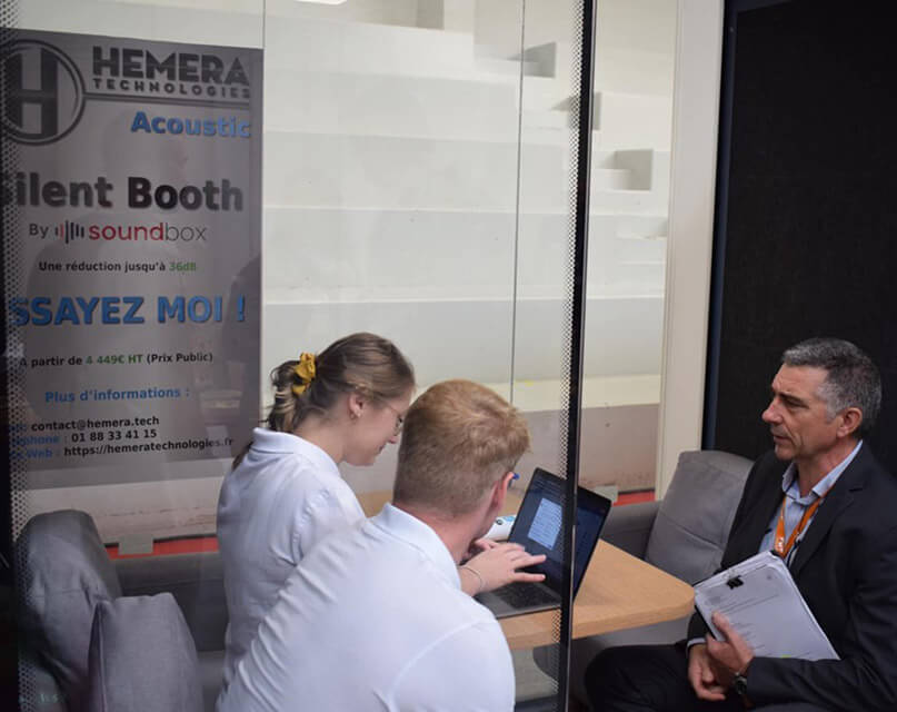 Three people meeting inside a green office privacy pods